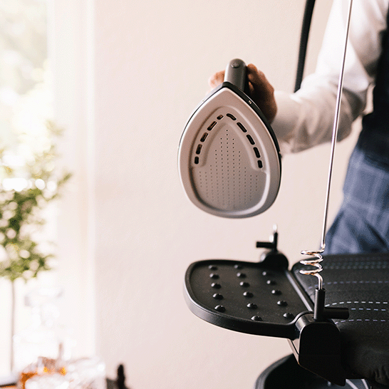 A well dressed man holding a Laurastar Smart iron with its protective sole plate